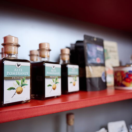 rotes Verkaufsregal mit mehreren braunen Glasflaschen Alte Pomeranze