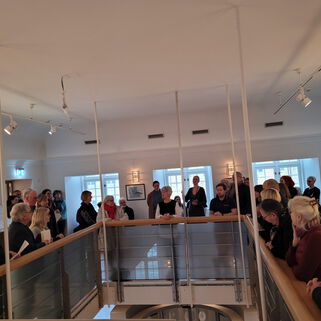 Viele Besucherinnen und Besucher stehen in der Galerie einer Ausstellung von Karin Camara