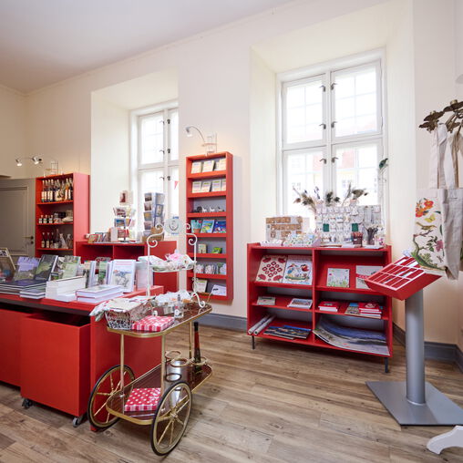 Viele rote Regale mit Artikeln des Shops, vorwiegend Bücher