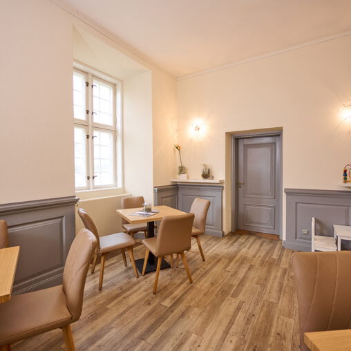 3 Tische mit vielen braunen Lederstühlen im Cafe des 3 Königinnen Palais