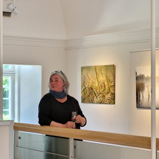 Künstlerin Kerstin Zegenhagen in der Ausstellung mit einem Glas Sekt in der Hand
