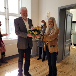 Sabine K. Lauffer überreicht dem Künstler Gerd Frick einen Blumenstrauss.