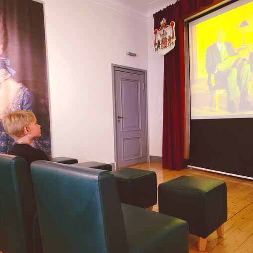 Junge sitzt im Erlebniskino der Ausstellung und sieht sich einen Film an