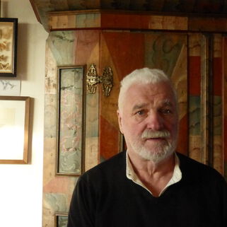 Künstler Gerd Frick  vor einem bunten Holzschrank