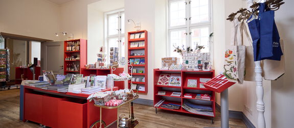 Viele rote Regale mit Artikeln des Shops, vorwiegend Bücher