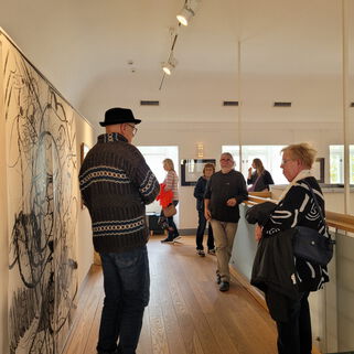 Künstler Peter Hecht neben einem Bild und weitere Personen