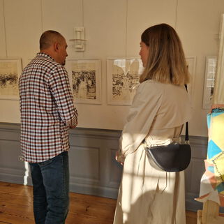 1 Mann und eine Frau sehen sich Bilder der Ausstellung Bun Venit an.