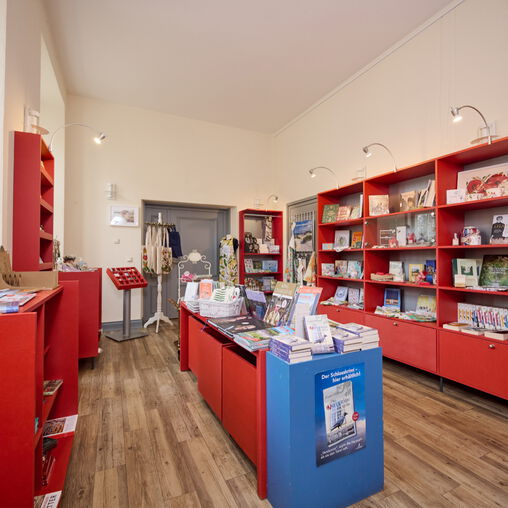 Viele rote Regale mit Artikeln des Shops, vorwiegend Bücher