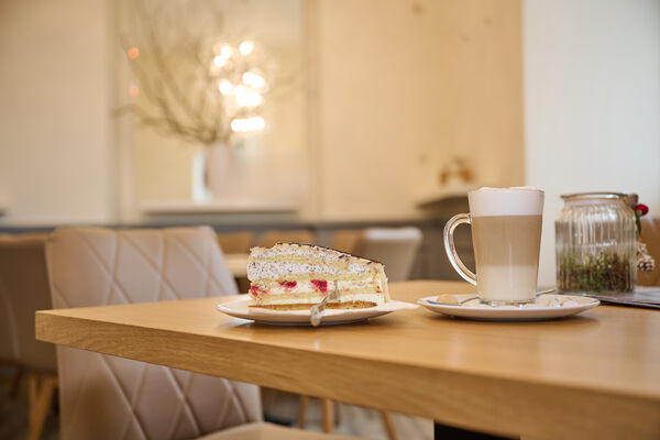 Stück Torte auf einem Teller, Glas Latte Macchiato auf einem Tisch des Café