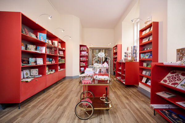 Viele rote Regale mit Artikeln des Shops, vorwiegend Bücher
