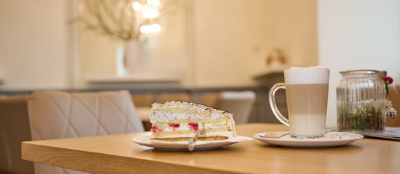 Stück Torte auf einem Teller, Glas Latte Macchiato auf einem Tisch des Café