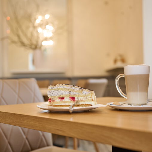 Stück Torte auf einem Teller, Glas Latte Macchiato auf einem Tisch des Café